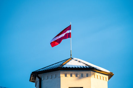 Latvian Flag on the flagpole fluttering in the wind against blue clear sky background, copy spaceの写真素材
