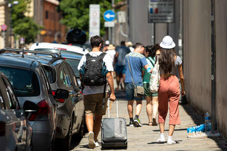 Pisa, Italy - August 9, 2021: city residents and tourists with bags walk along the sidewalk along a line of parked carsのeditorial素材