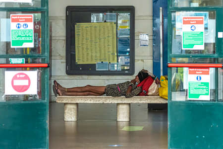 Pisa, Italy - August 10, 2021: woman on a hot day, finding shade, lying on the bench at the train...