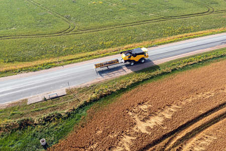 combine harvester on the road between agricultural fields, view from aboveの写真素材