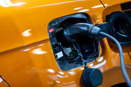 plug of the charging cable plugged into an electric car, charging an electric car at the station