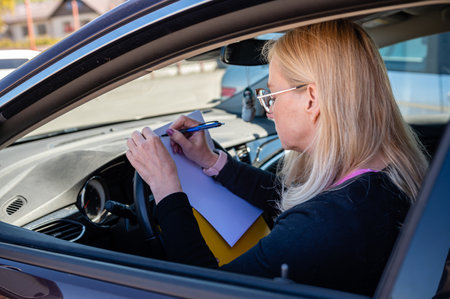 middle aged business woman in glasses in car working with documents, mobile technology conceptの写真素材