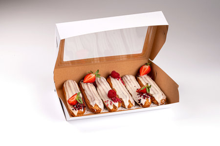 packing box with eclair with glaze and strawberries, isolated on white, close-up