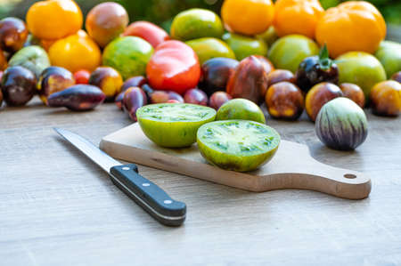 table with a cutting board with sliced tomatoes and different colored tomatoes in the backgroundの写真素材