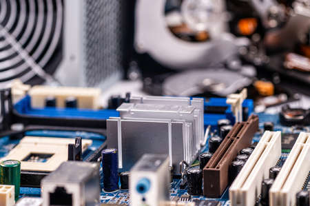 fragment of computer circuit board with components on the background of defocused power supply fans