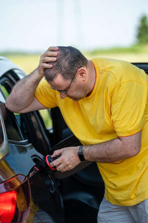 worried and surprised emotional man at open car tank, fuel price rise concept