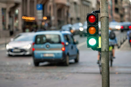 a city crossing with a semaphore on blurred background with cars in the evening streets, green lightの写真素材