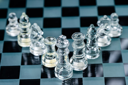 clear glass chess figures arranged in a row reflecting in glass chessboard. Isolated on blackの写真素材