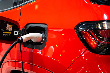 plug of the charging cable plugged into an electric car, charging an electric car at the station