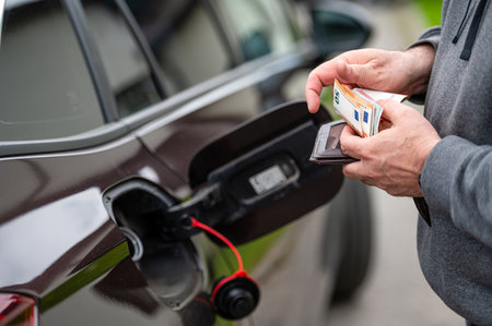 a man s hand counts money while standing at an open fuel tank, the concept of rising fuel pricesの写真素材