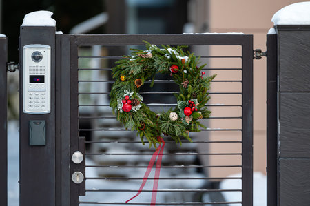 Christmas wreath on a metal gate at the entrance of a residential building, close-upの写真素材