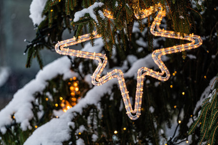 Christmas toys on the Christmas tree. Snow on a branch. Street decoration in winter.の写真素材