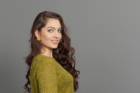 close-up portrait of beautiful sensual woman with long curly hair against gray backgroundの写真素材