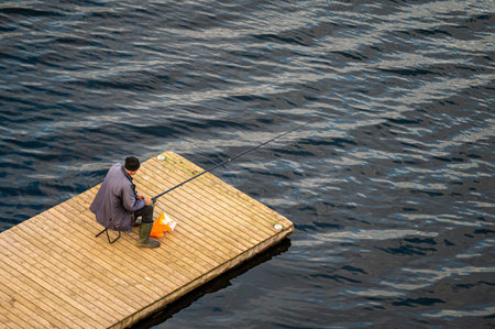 Fisherman with fishing rod on  the wooden bridge, rear view from aboveの写真素材