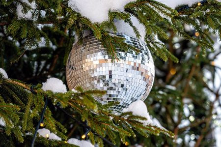 Christmas disco ball decoration on a snowy fir tree branch. Selective focus, shallow depth of fieldの写真素材