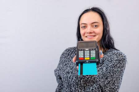 caucasian female holding payment terminal and giving it to the customer can pay with credit cardの写真素材