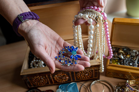 Wooden treasure chest with valuables. A woman holds beads, necklaces and other jewelry in her hands.の写真素材