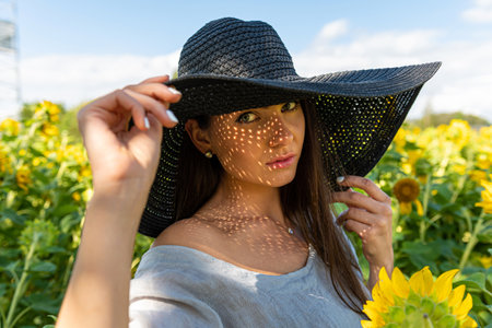 portrait of beautiful sensual brunette in elegant hat, pattern of shadows falling on her faceの写真素材