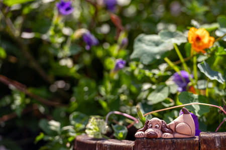 Clay dog figure in the garden among plants and flowers, close-upの写真素材