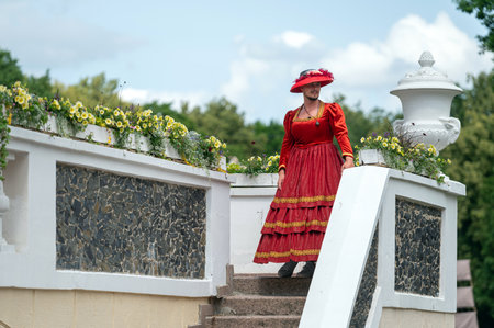 Pakruojis, Lithuania. July 1, 2023: Animator in vintage women's costume on manor stairs at flower festival.のeditorial素材