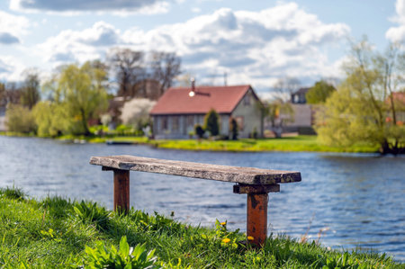 Wooden bench on the bank of the river on a cloudy spring day. Spring landscape.の写真素材