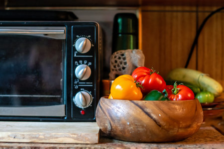 Kitchen interior with microwave oven, tomatoes and other vegetables in wooden bowlの写真素材