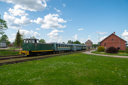 Aluksne, Latvia - May 24. 2023: Aluksne train station with narrow gauge train in front.のeditorial素材