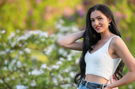 A woman with long black hair stands near a flowering tree. Shallow depth of feldの写真素材