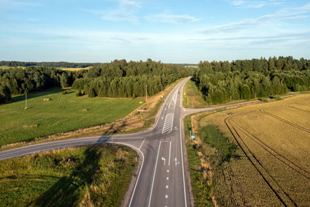 A rural road intersection with a car driving on the main road.
