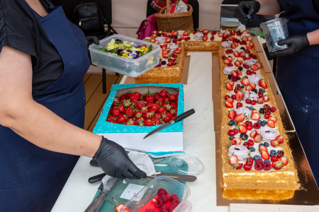 A large cake is being decorated with fresh berries and meringue. Shallow depth of feldの写真素材