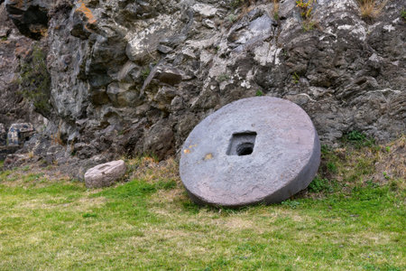 A large stone wheel rests near a rocky formation, showcasing ancient craftsmanship.の写真素材