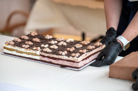 A person cuts a large chocolate cake into squares. Shallow depth of feldの写真素材