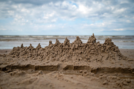 Sandcastle built on a beach with waves in the background during a cloudy dayの写真素材