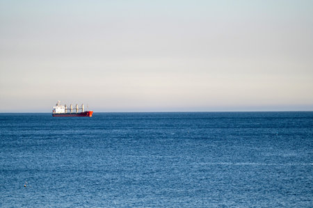 A cargo ship moves steadily across a tranquil sea on a clear day.の写真素材