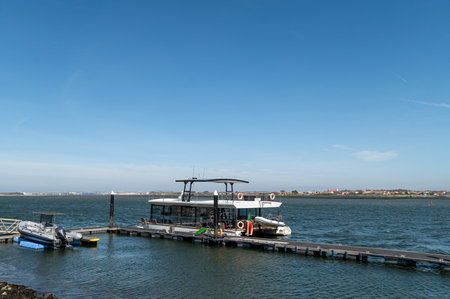 A tourist boat is moored at a pier with clear skies over the water.の写真素材