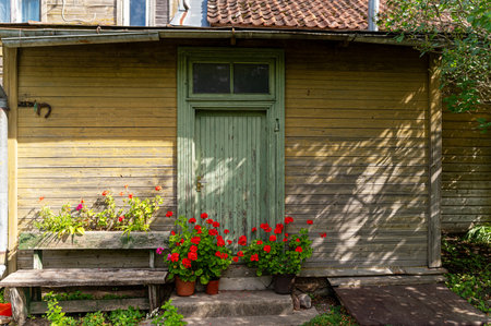A quaint wooden house with a green door surrounded by vibrant flower pots.の写真素材