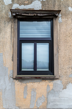 A vintage-style window framed by weathered plaster on a rustic wall shows character and age.の写真素材