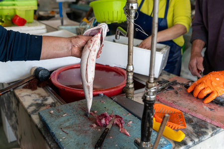 Preparing fresh fish at a local market in the early morning hours of a bustling cityの写真素材