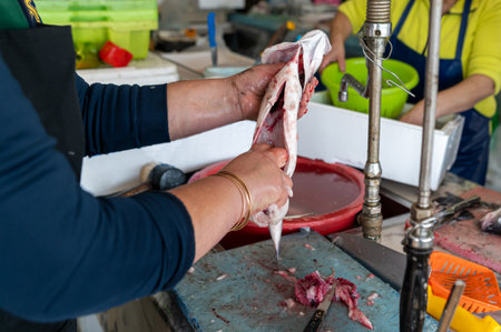 Preparing fresh fish at a market stall in the early morningの写真素材