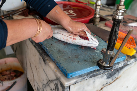 A person skillfully filleting fish at a bustling market stall during the morning hours.の写真素材