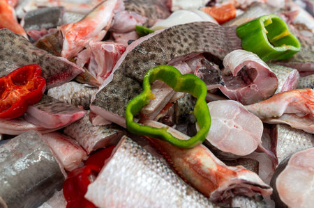 A variety of fresh fish with sliced vegetables ready for cooking in a market setting.の写真素材