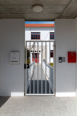 The entrance features a gated pathway leading to a classic building with red doors.の写真素材