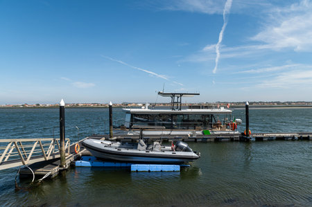 Tourist boat docked at a waterfront pier on a sunny day by the riverの写真素材
