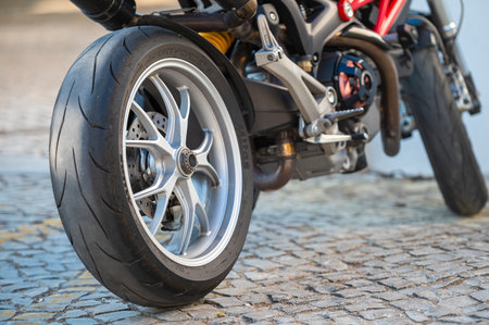 A motorcycle tire rests on textured cobblestone stones under natural sunlight.