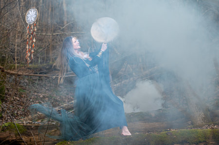 A woman plays a drum in a foggy forest. Shallow depth of feldの写真素材