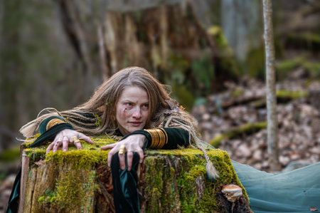 A woman leans on a moss-covered tree trunk in a forest. Shallow depth of feldの写真素材