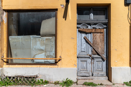 Abandoned structure with a weathered door and boarded window, showcasing neglect and decay.の写真素材