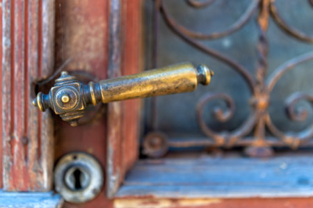 Brass door handle and lock on a weathered wooden door with intricate ironwork in an antique styleの写真素材