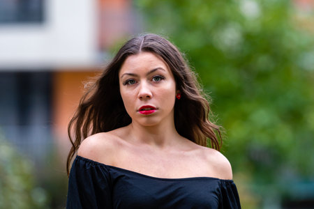 A young woman stands outdoors with soft, flowing hair and a confident expression.の写真素材