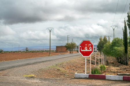 Traffic stop sign with Arabic script near rural road in Moroccoの写真素材